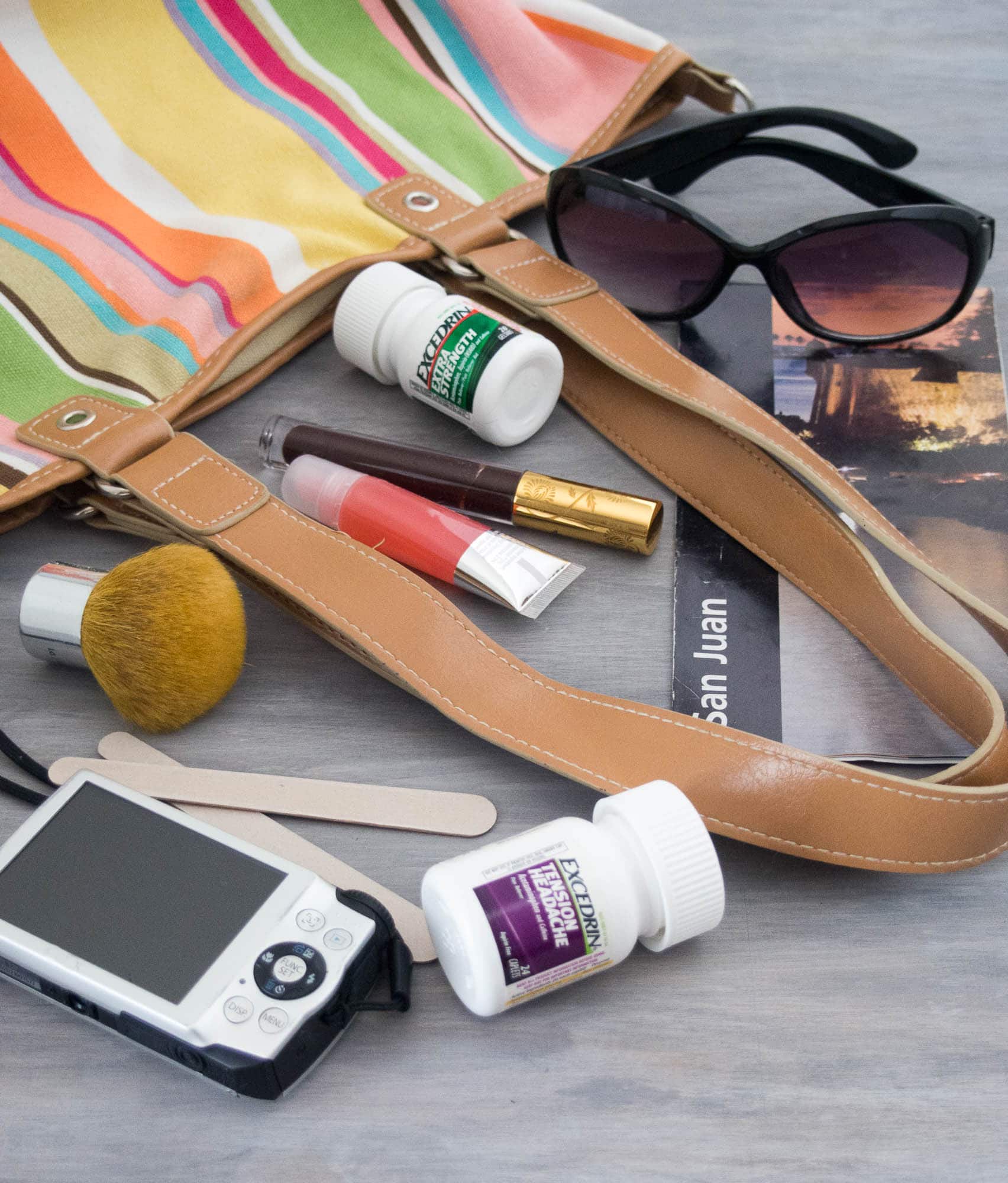A purse with sunglasses, a cell phone, and other items.