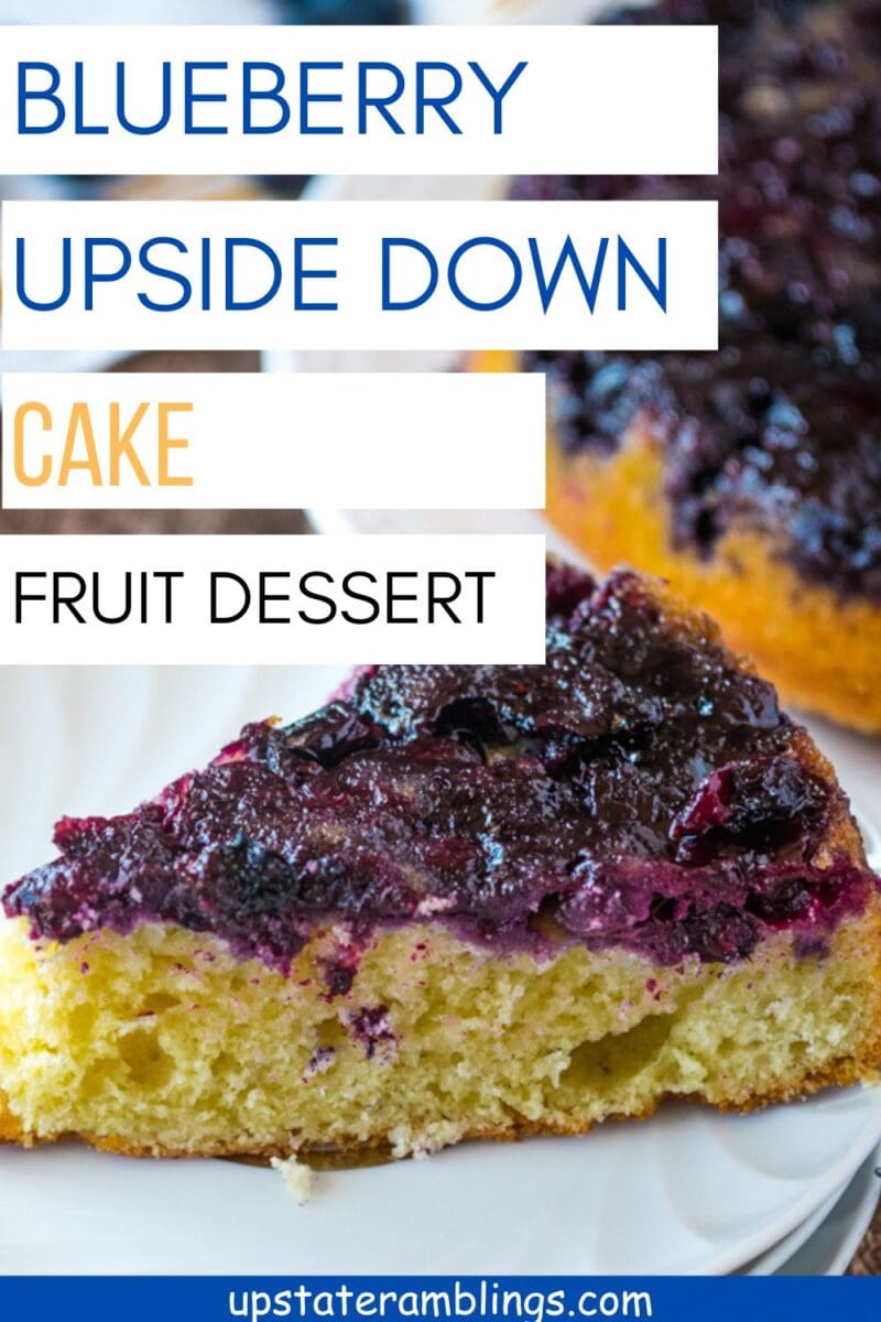 A slice of Blueberry Upside Down Cake sits on a white plate, displaying its glossy fruit topping and golden-yellow cake base.