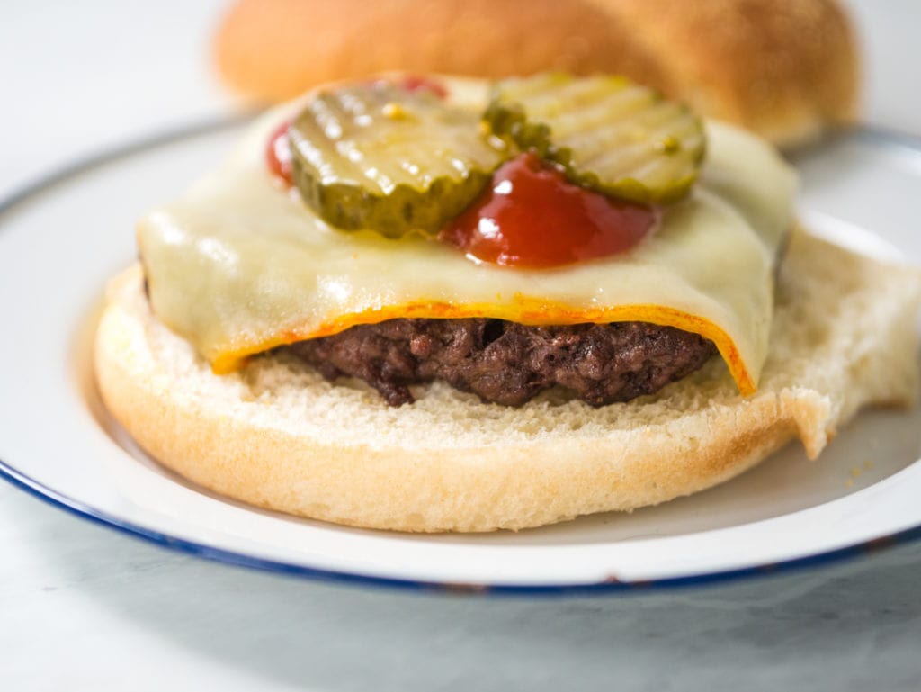 closeup of air fryer burger with cheese, ketchup and pickles