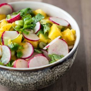 A bowl with mango and radishes in it.