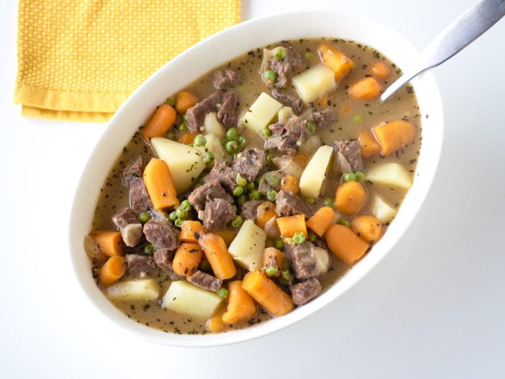 big bowl of beef stew with carrots, potatoes and peas