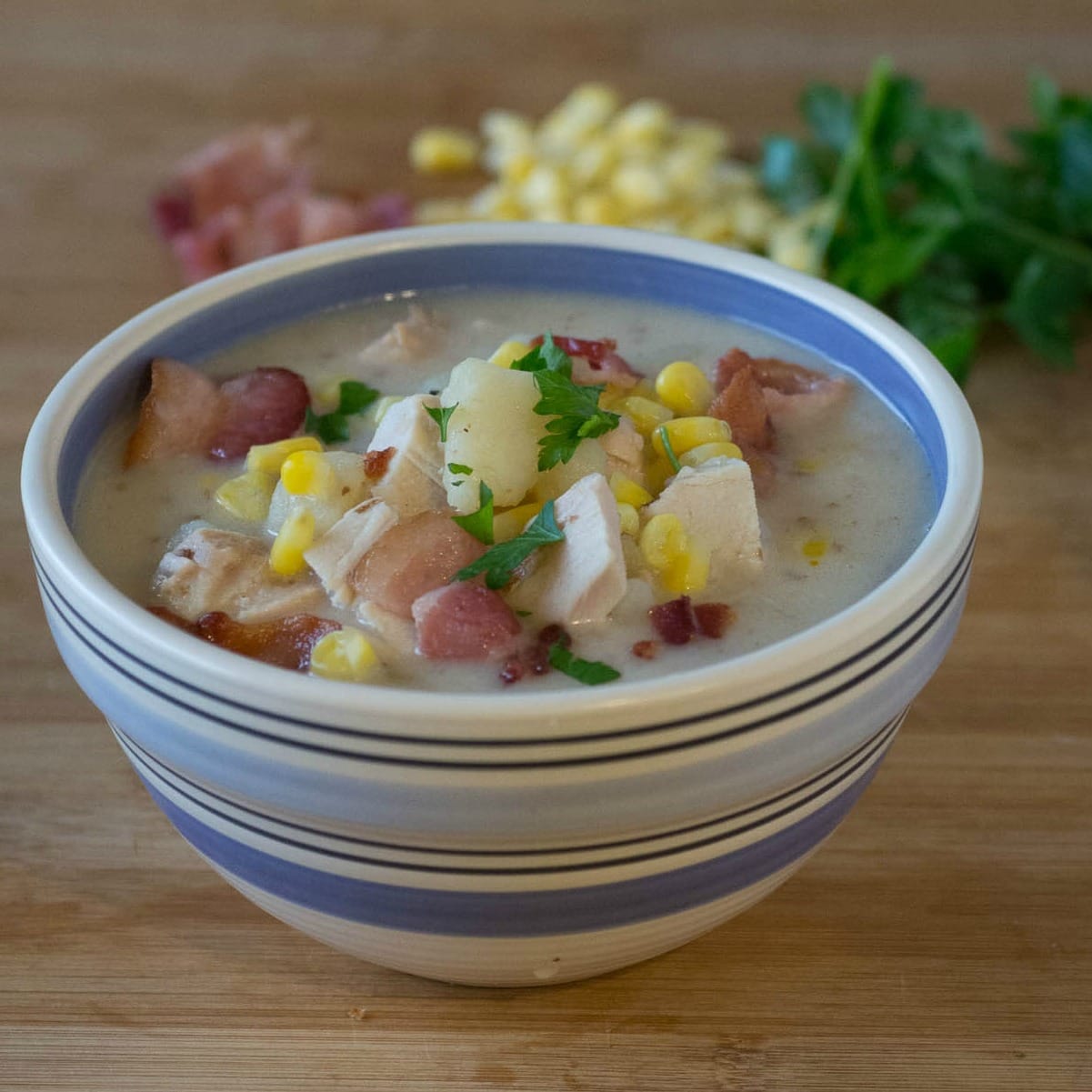 A bowl of chowder with corn and bacon.