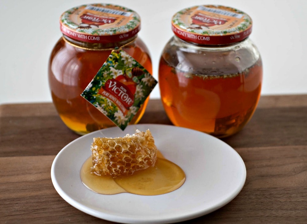Two jars of honey on a white plate.