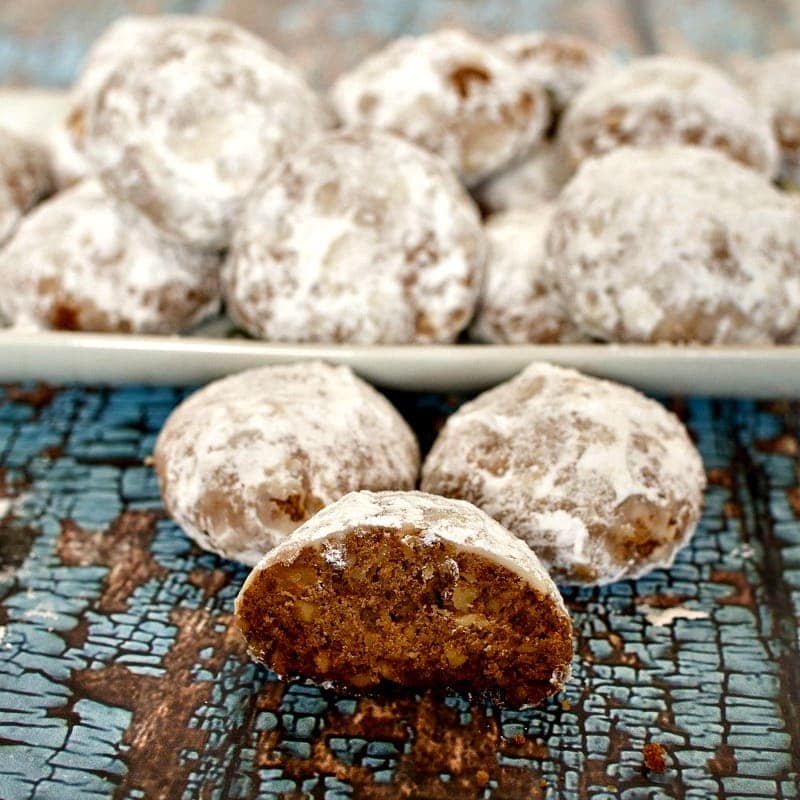 A plate of Russian tea cakes with powdered sugar on it.