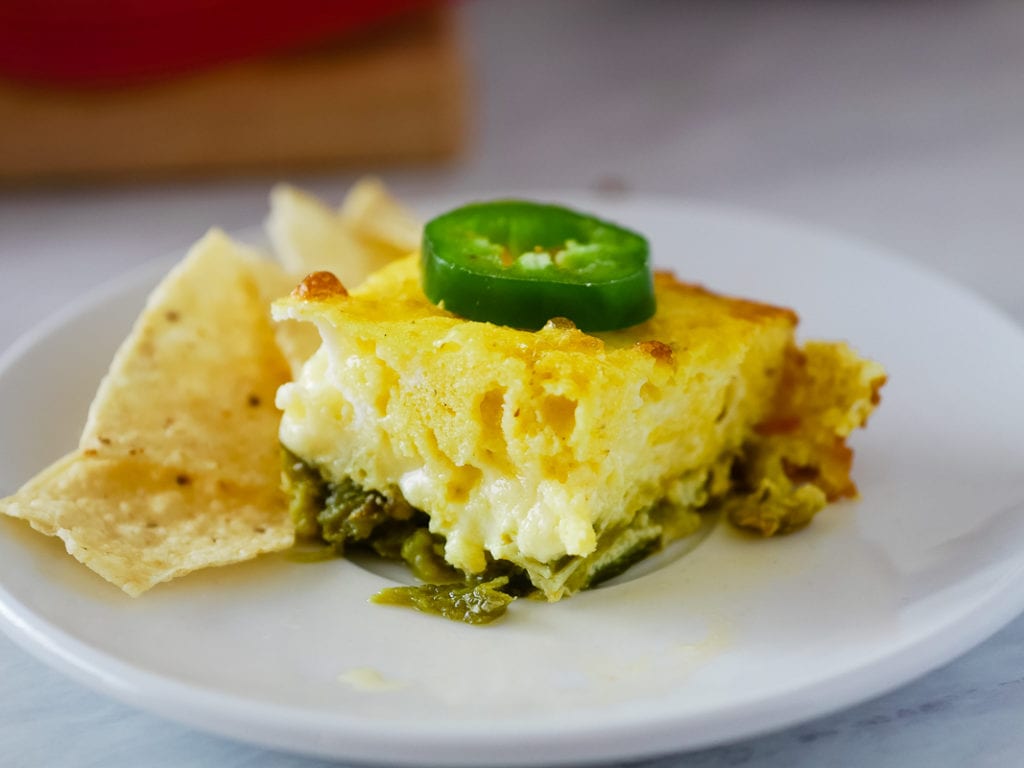 chile relleno casserole square on a plate with jalepeno on top and tortilla chips