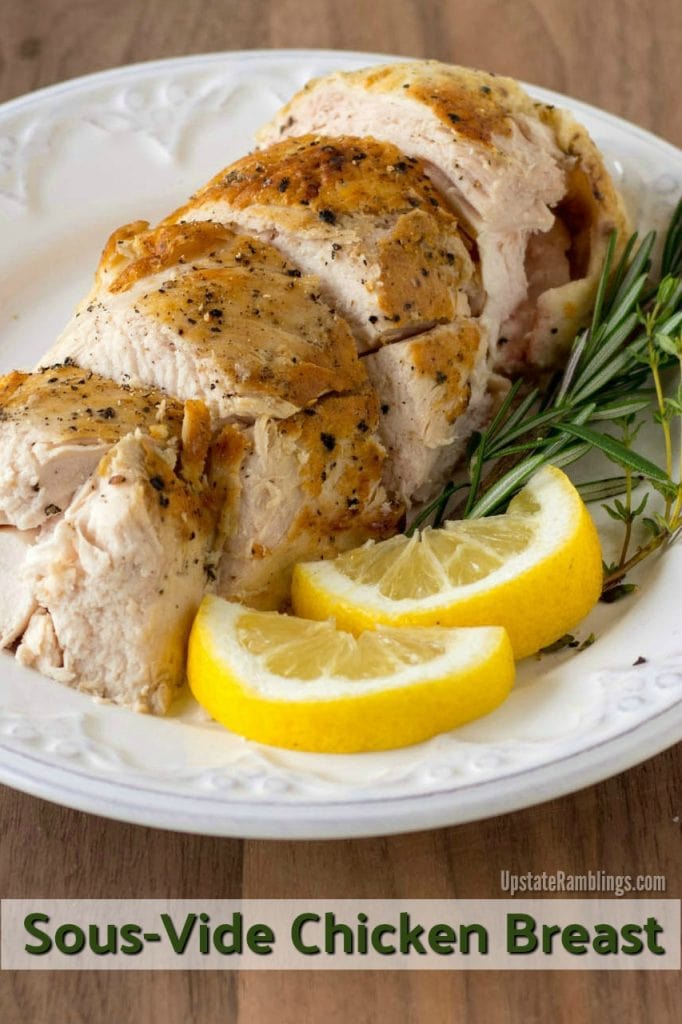 chicken breast on a white plate with rosemary and lemon