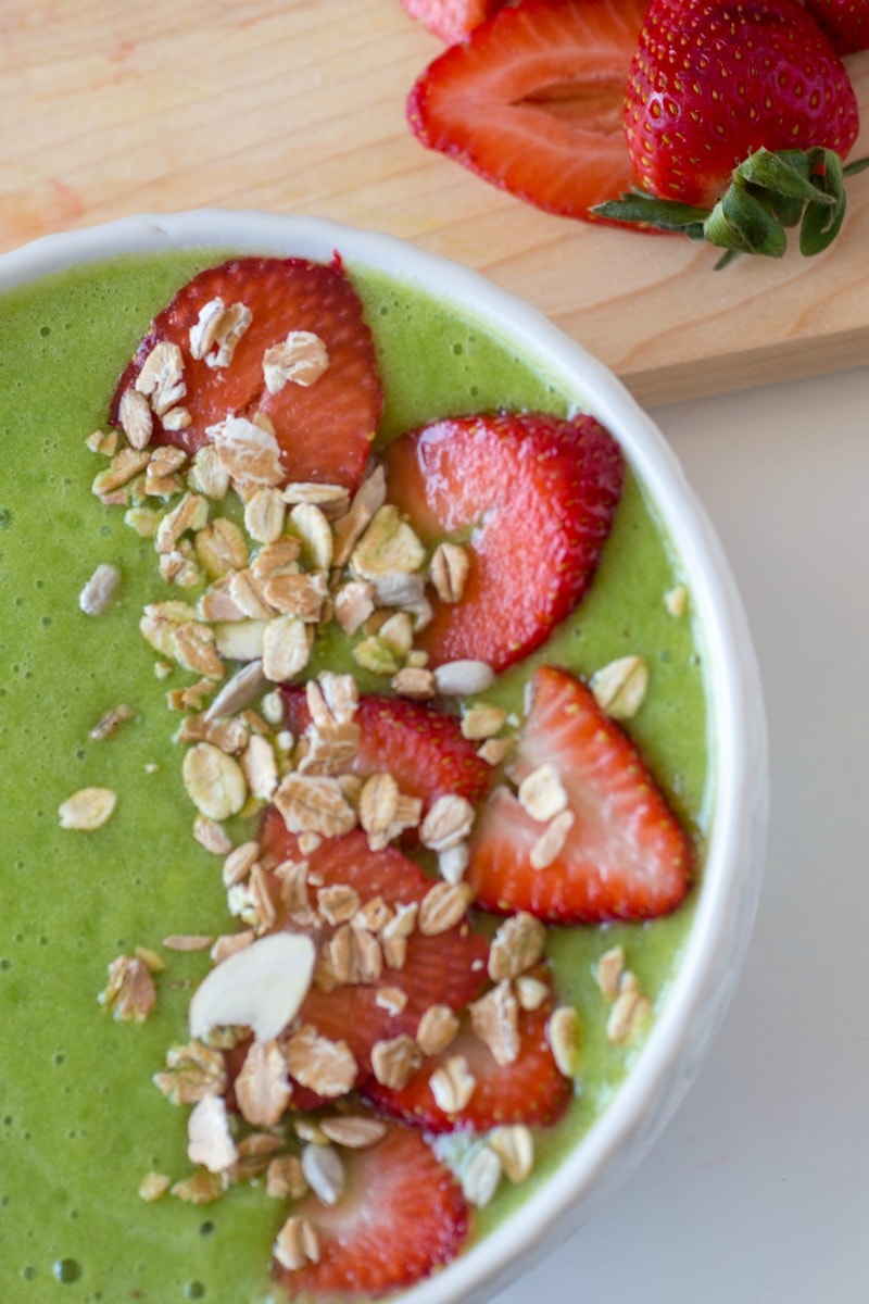 Healthy Vegan Green Smoothie Bowl topped with strawberries and granola