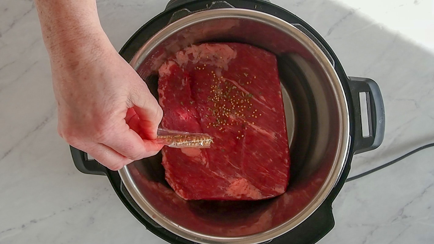 Adding the spice packet to the corned beef in the Instant Pot