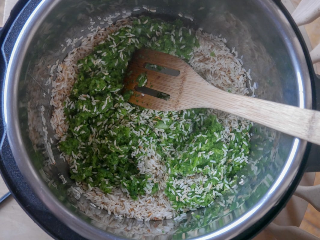 A pot filled with Arroz Verde, a traditional dish of rice and greens, served with a wooden spoon.