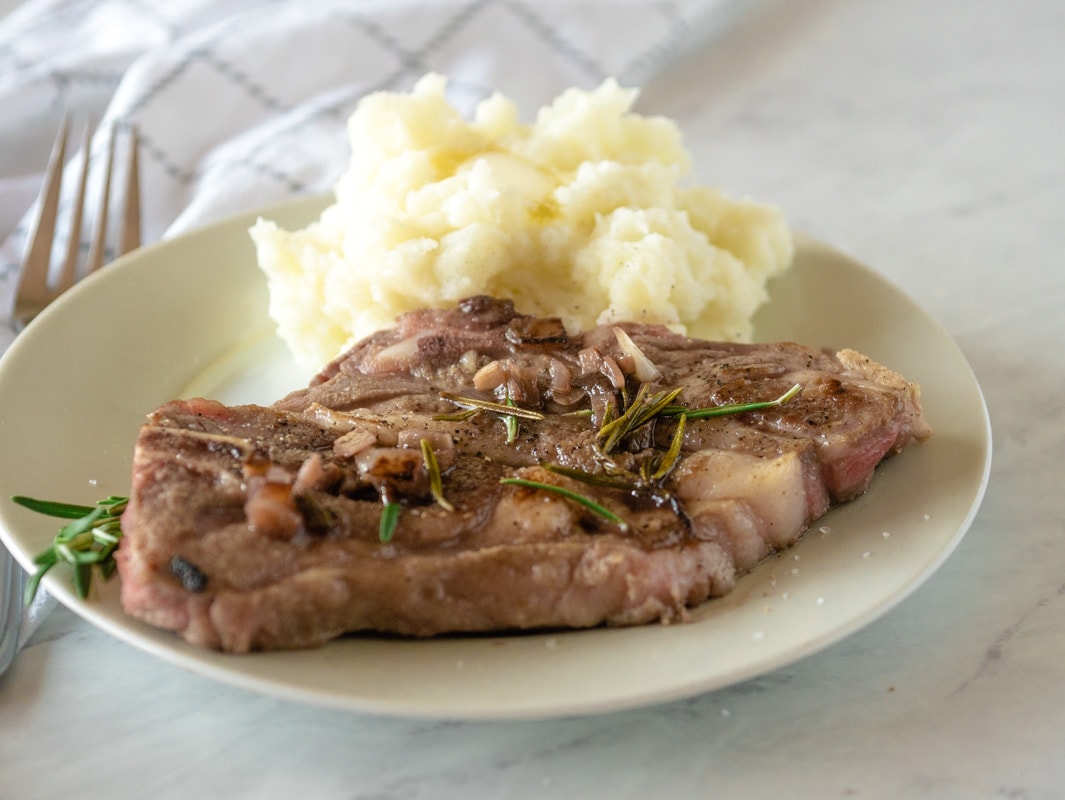 Plate with sous vide lamb chop, mashed potatoes and rosemary