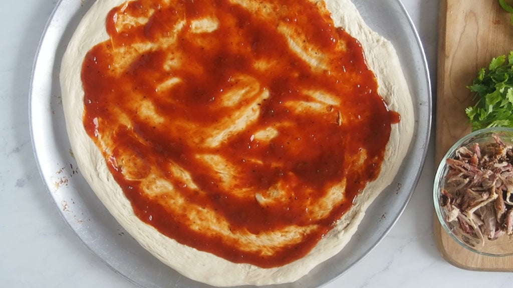 pizza dough with BBQ sauce covering it