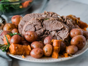 sliced pressure cooker leg of lamb on plate with potatoes and carrots