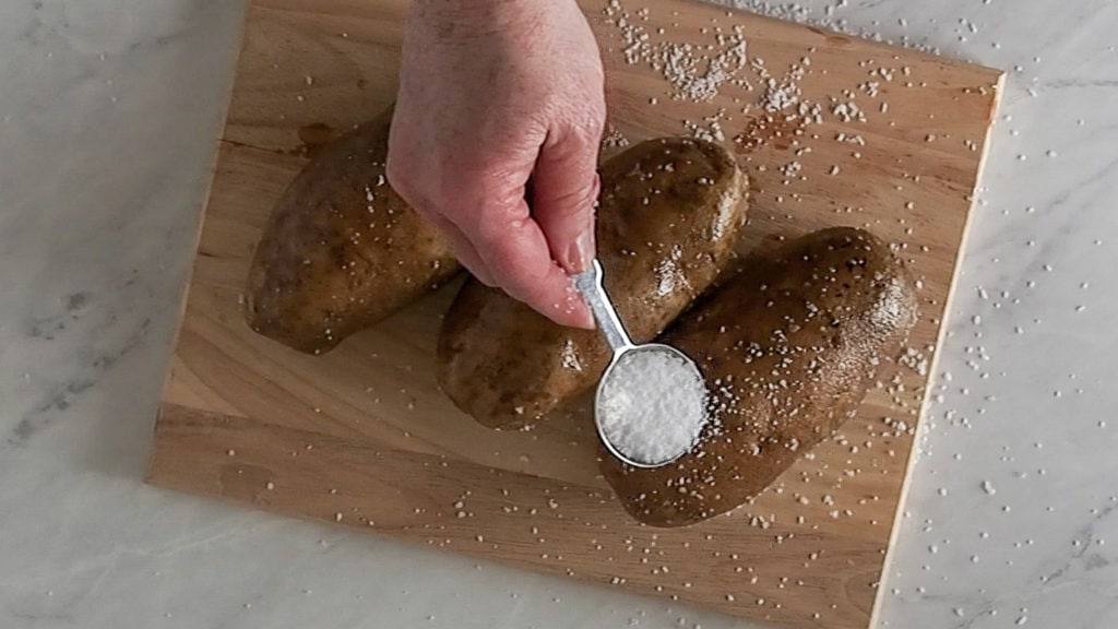 putting salt on the baked potatoes