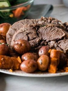 A plate of roast beef with potatoes and carrots.