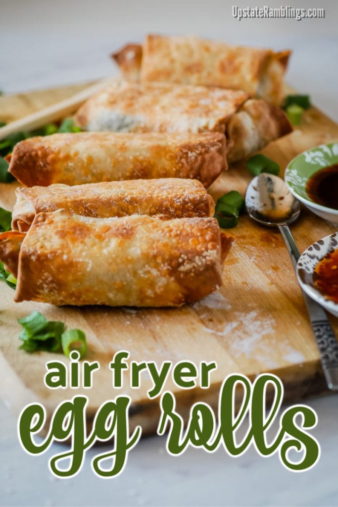 homemade air fryer egg rolls on a wooden cutting board with bowls for dipping