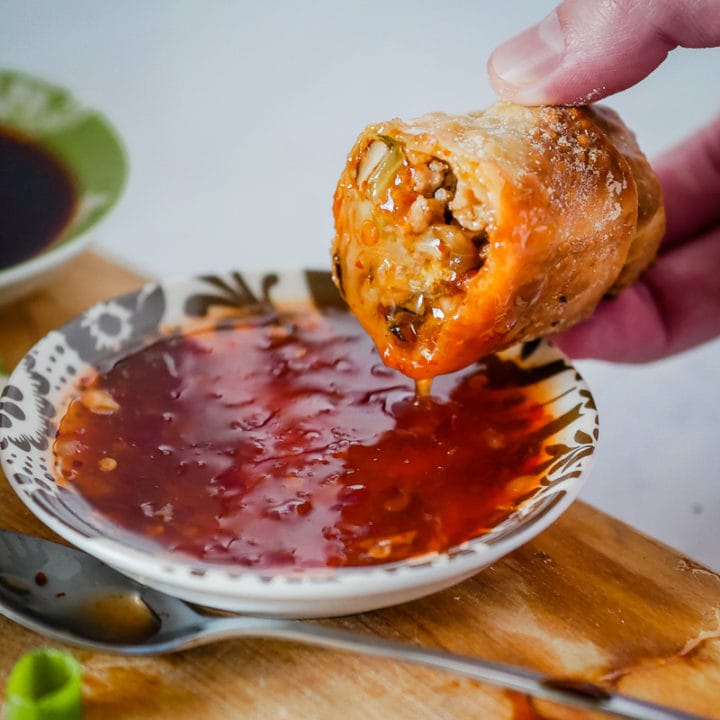 a homemade egg roll dipped into sweet chili sauce