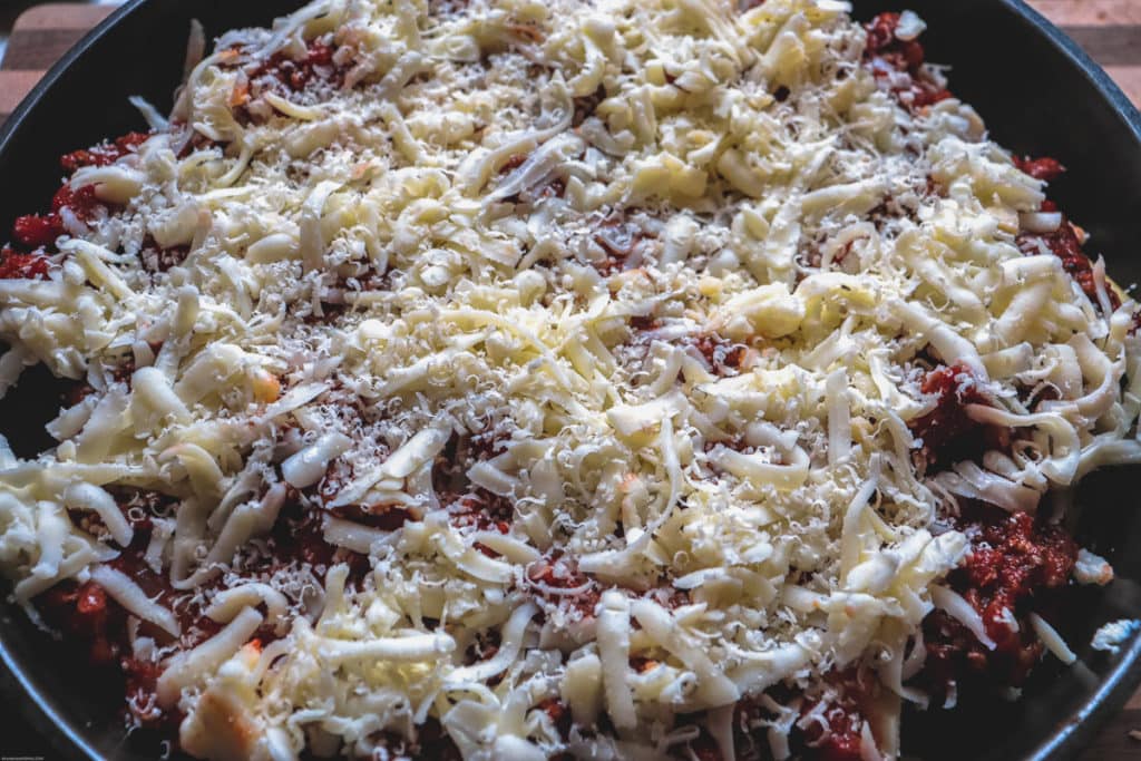 topping the stuffed manicotti with cheese