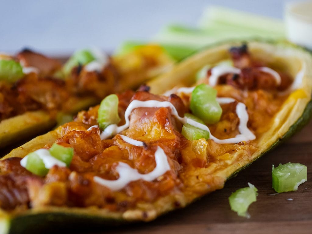zucchini boats with chicken on a wooden cutting board