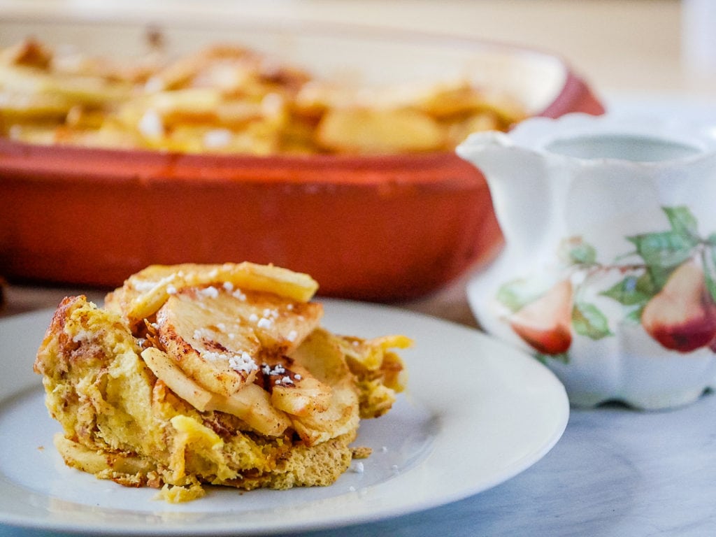 serving of baked french toast casserole on a plate with the casserole dish in the background