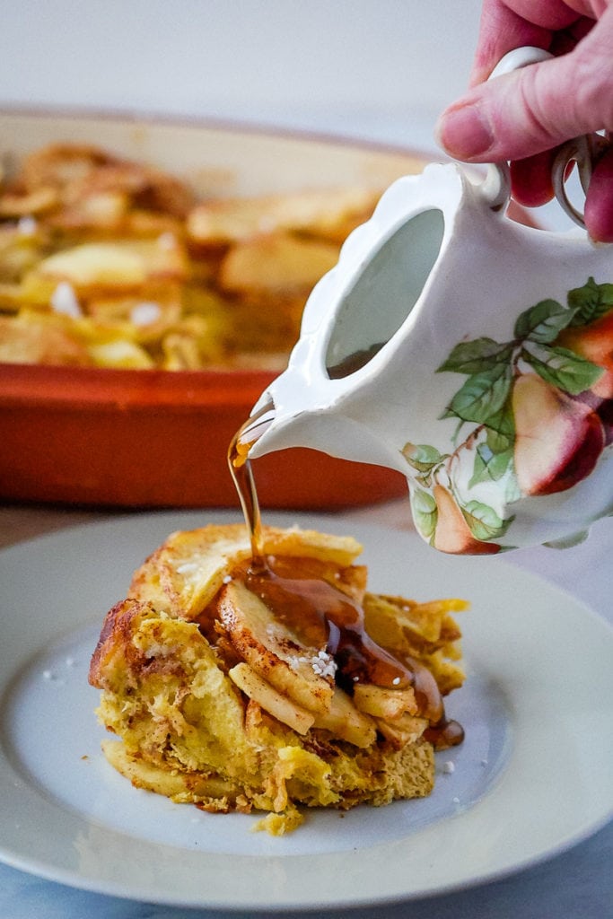 pouring syrup on a serving of baked apple french toast casserole
