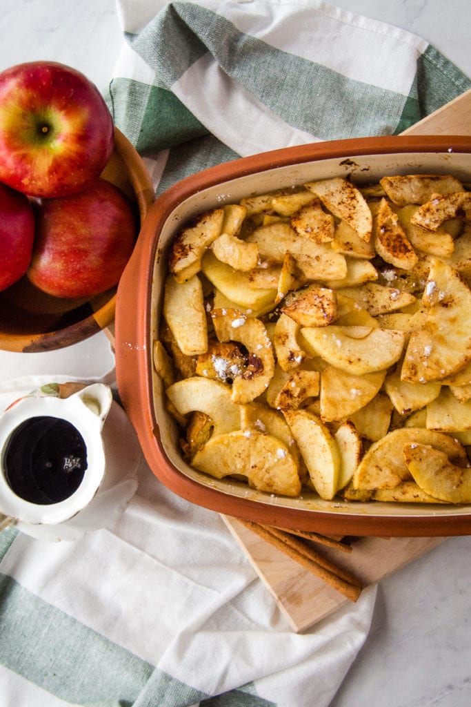 apple french toast casserole with a pitcher of syrup and apples