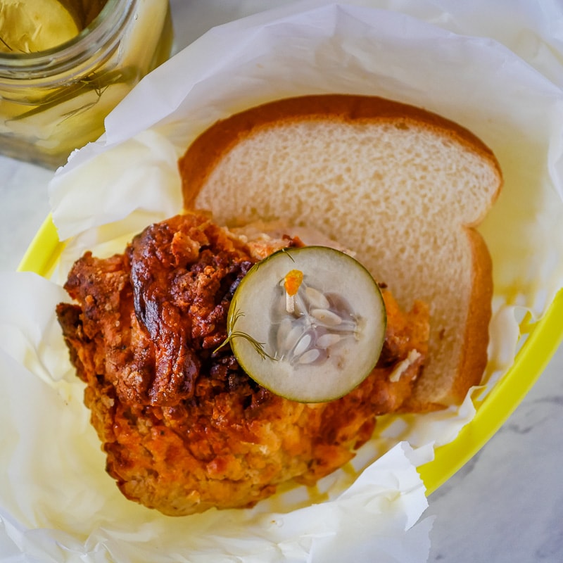 Overhead shot of spicy Nashville chicken served with bread and a pickle