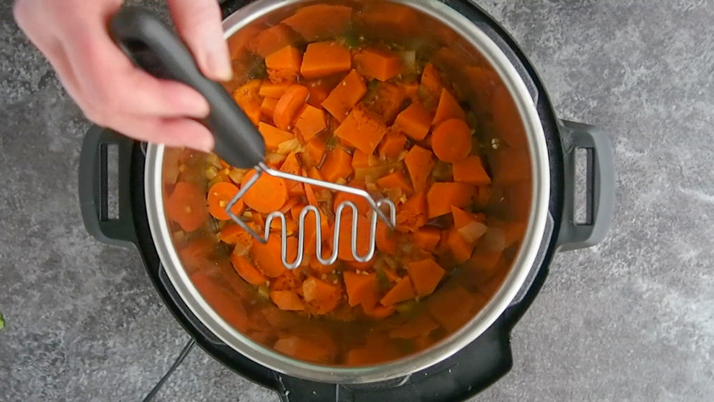 mashing the vegetables in the Instant Pot chicken stew