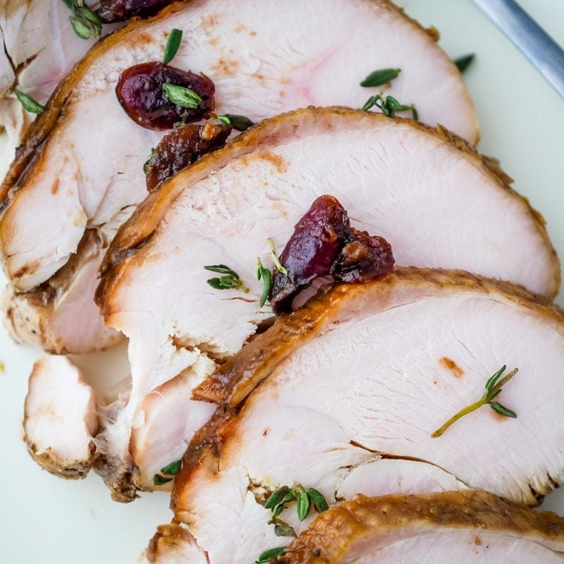 Roasted turkey with cranberry sauce on a white plate.
