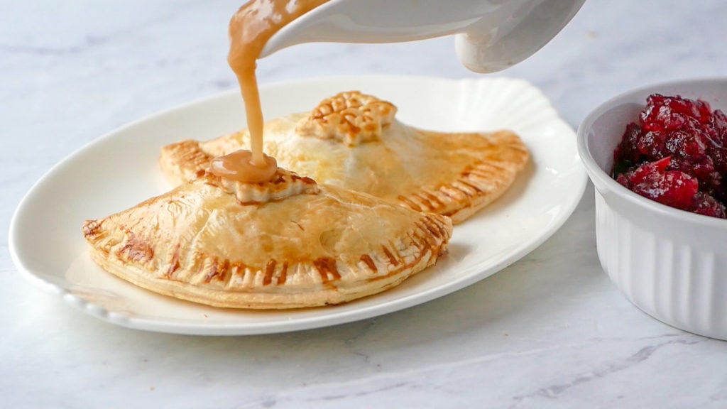 pouring gravy over the thanksgiving hand pies