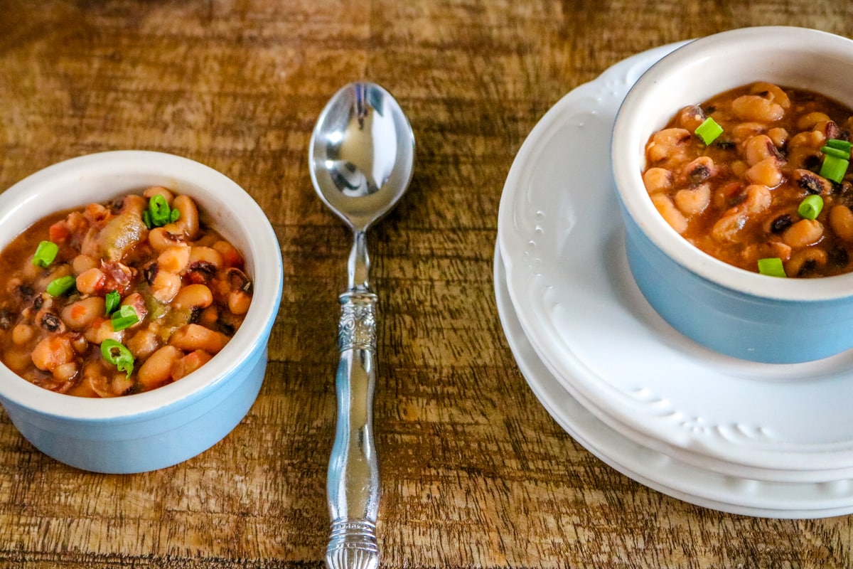 Two bowls of Instant Pot black eyed peas on a wooden surface.