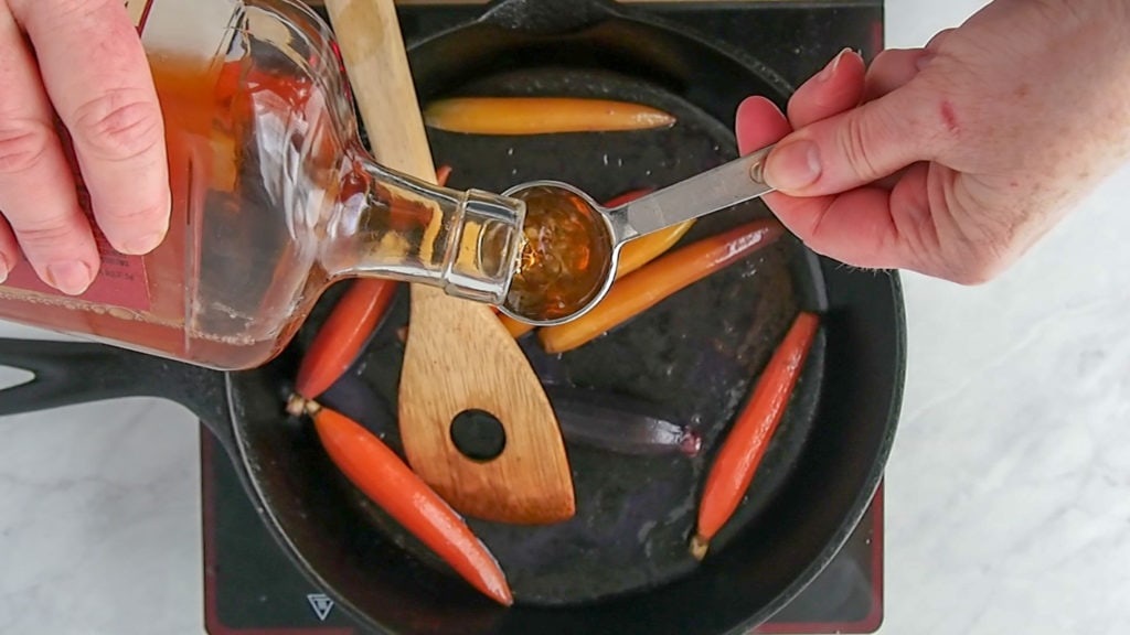 adding bourbon to the skillet to glaze carrots