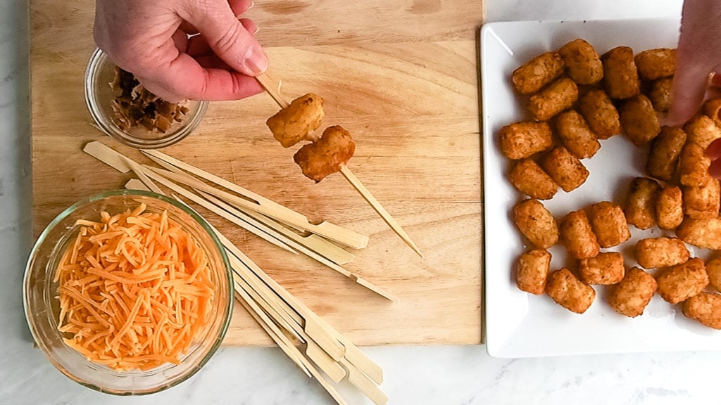 threading tater tots onto the skewers for tater tot appetizer