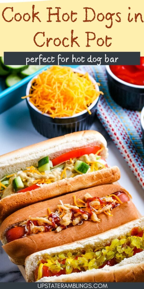 Three hot dogs in buns with various toppings are placed on a table alongside bowls of condiments and vegetables. Text at the top reads "Crock Pot Hot Dogs" and "perfect for a hot dog bar.
