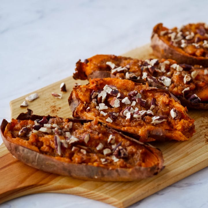 twice baked sweet potatoes topped with pecans on a cutting board