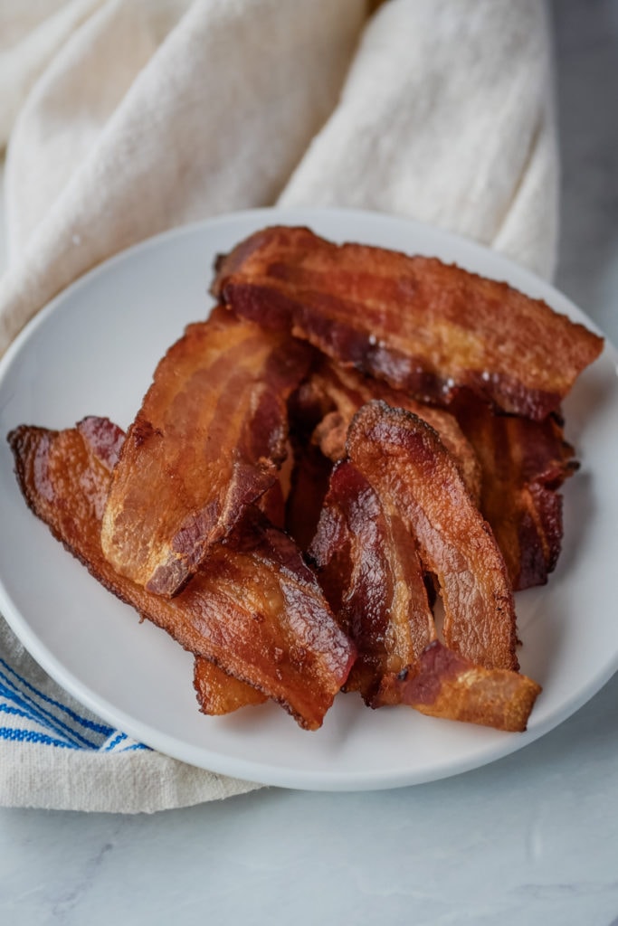 air fryer bacon on a plate with a dish towel in the background