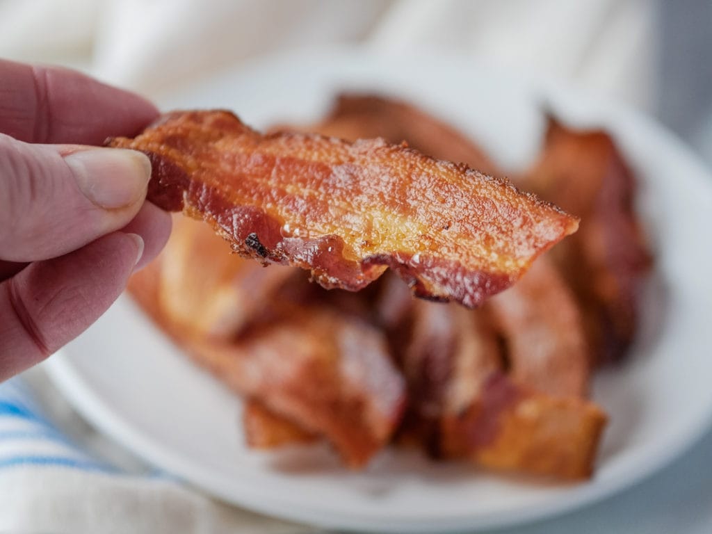holding a piece of air fryer bacon