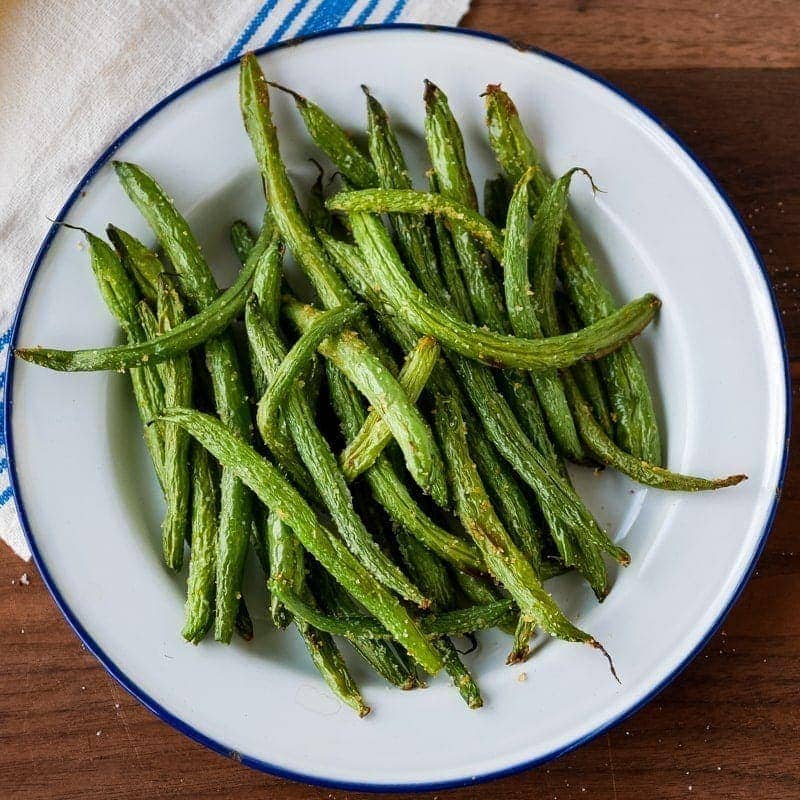 Closeup of air fryer green beans on a plate with a blue rim.