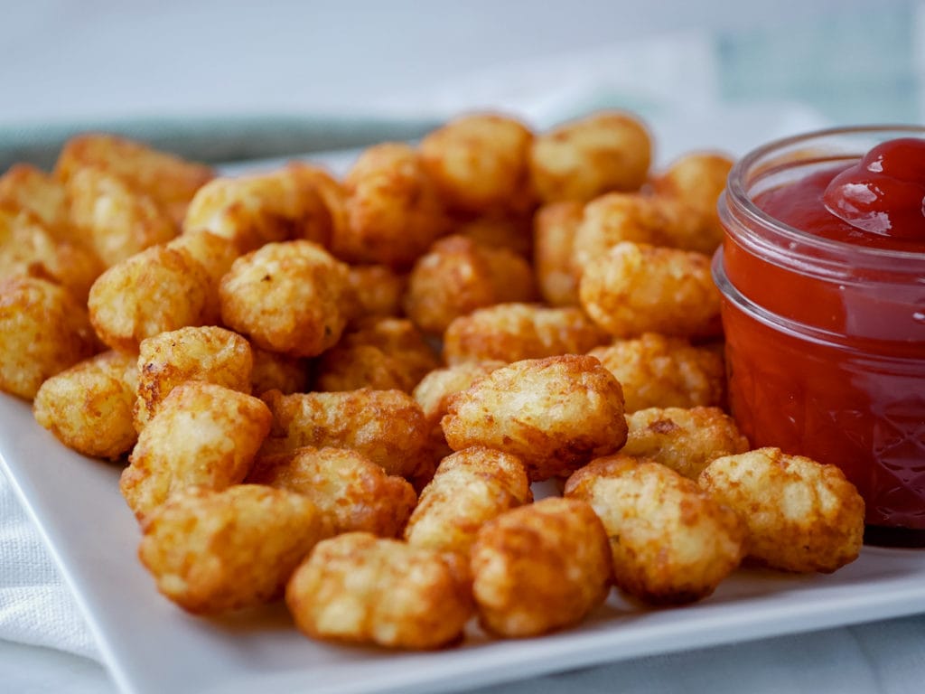 tater tots on a plate with spicy ketchup