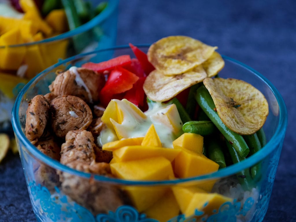 close up of Caribbean rice bowl with chicken, mango, beans, red pepper and plantain chips