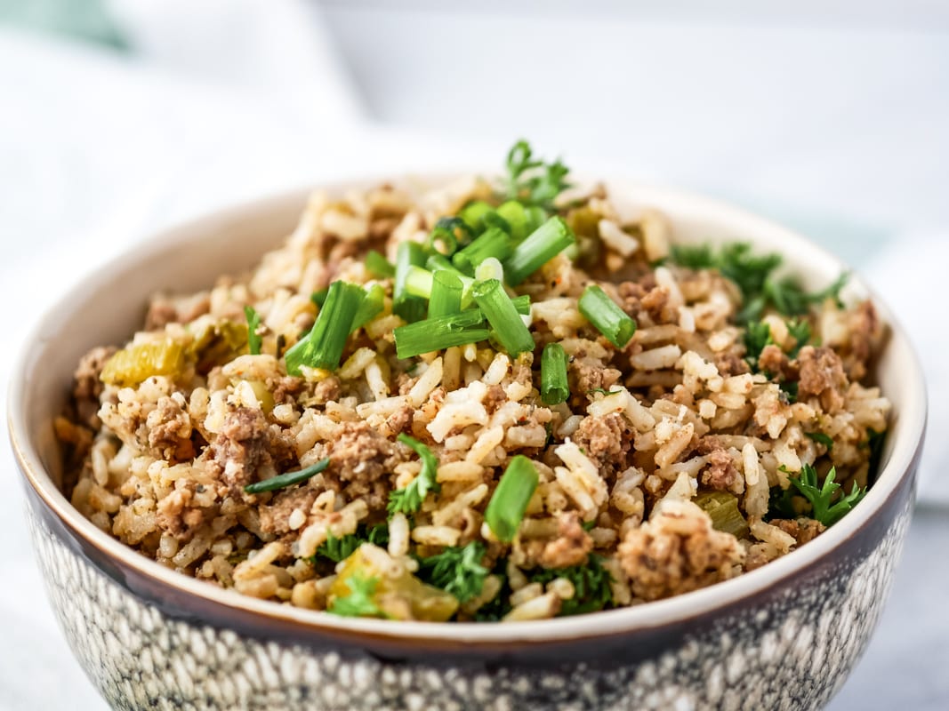 Dirty rice with ground beef in a bowl topped with green onions.