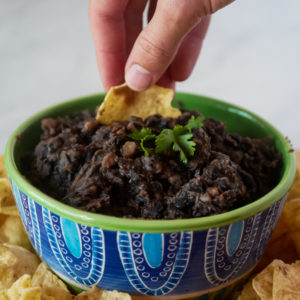 scooping out Instant Pot black beans in a bowl with chips