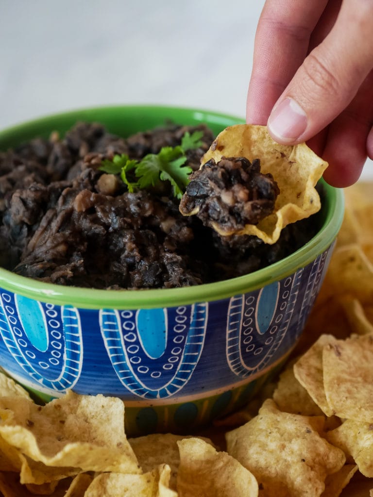 scooping up black beans with a tortilla chip