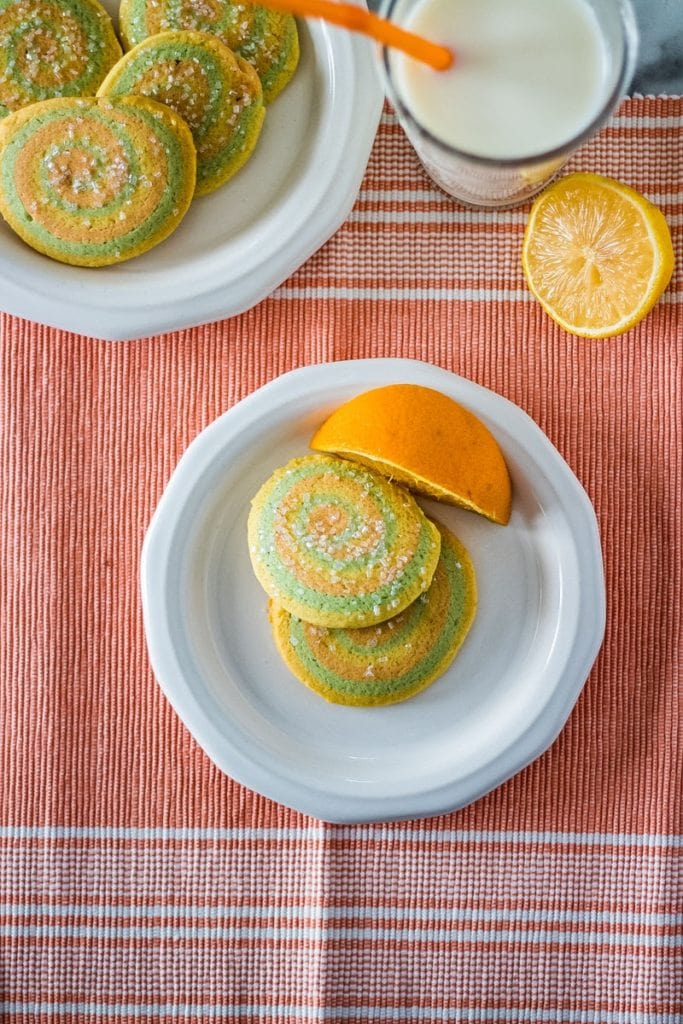 plate of spring pinwheel cookies with an orange on the plate