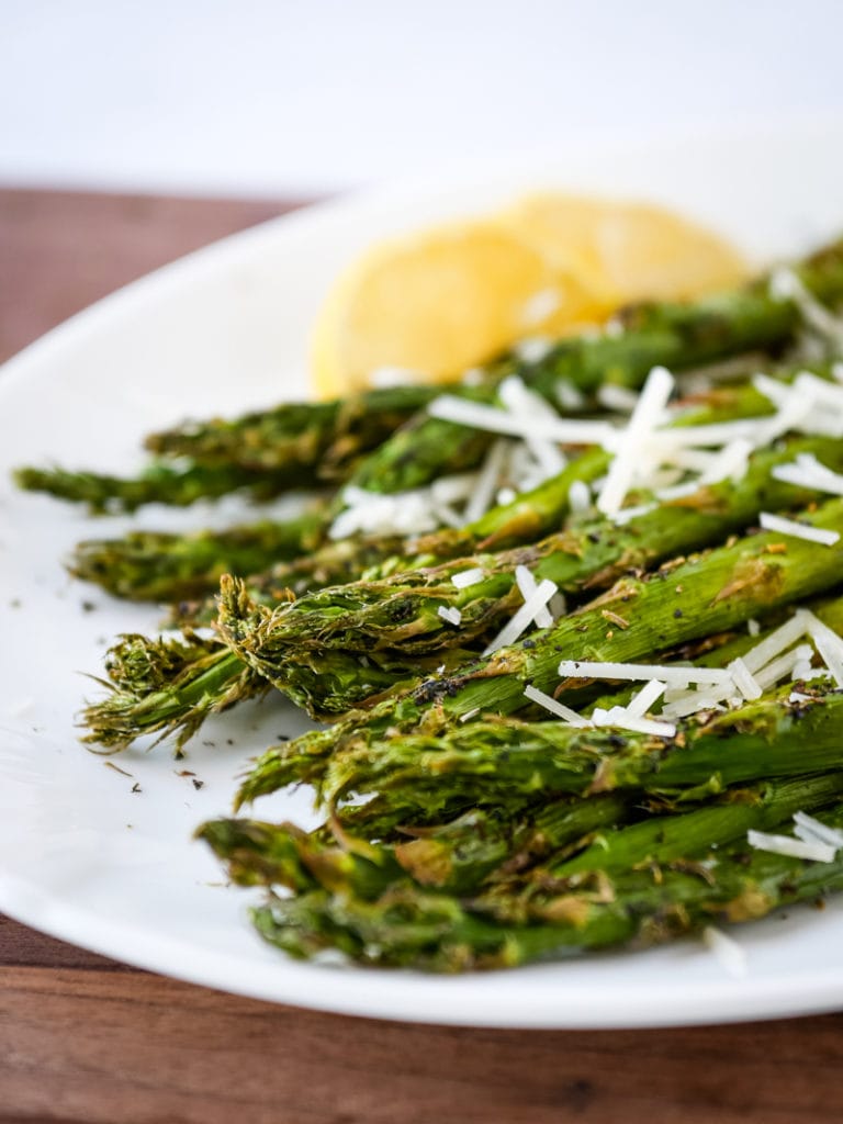 air fryer asparagus on a platter with lemon and cheese