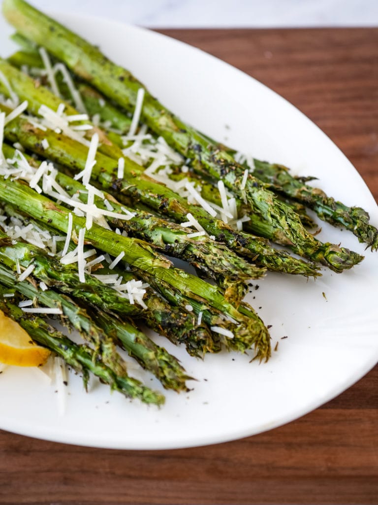 air fryer asparagus on a plate topped with Parmesan cheese