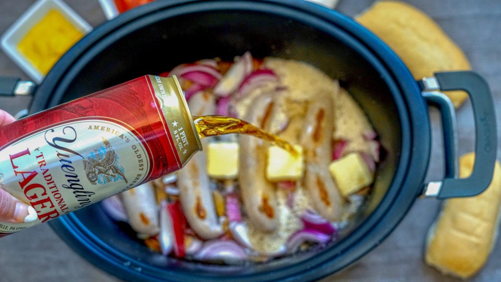 pouring beer into slow cooker while making beer brats