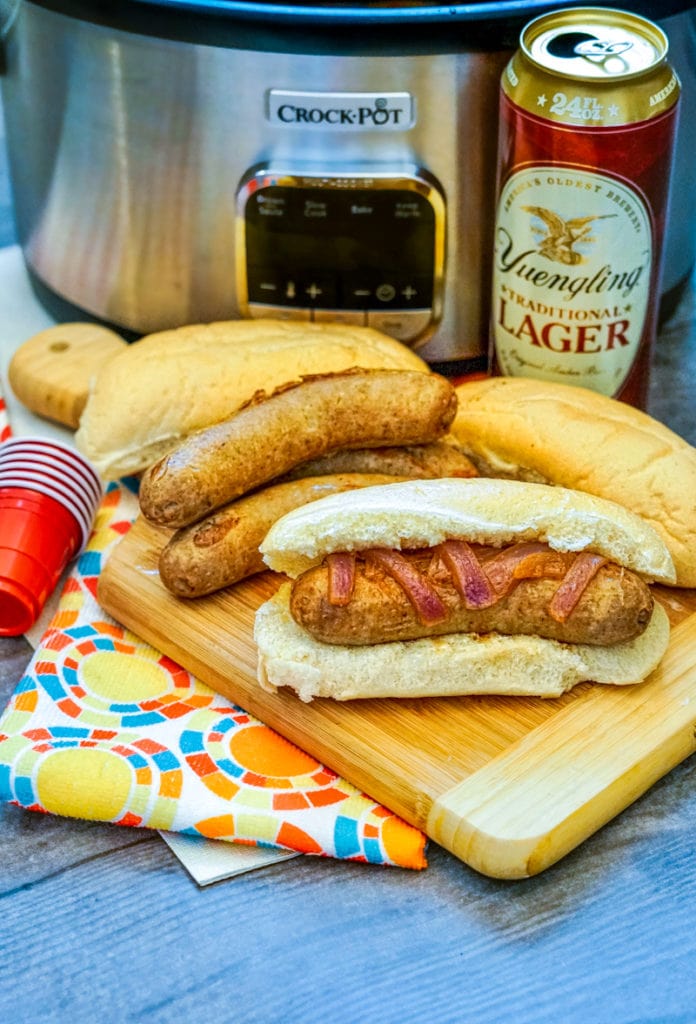beer brats in front of a crock pot with beer and buns 
