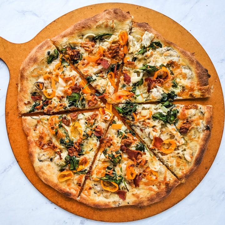 turkey pizza with spinach and peppers on a pizza peel