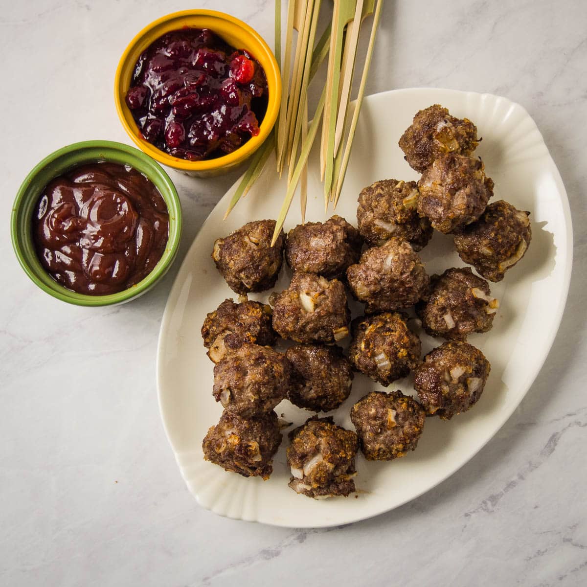 Plate of frozen meatballs with toothpicks sticking out of them.