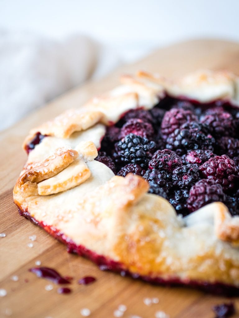 half of a berry galette on a wooden cutting board